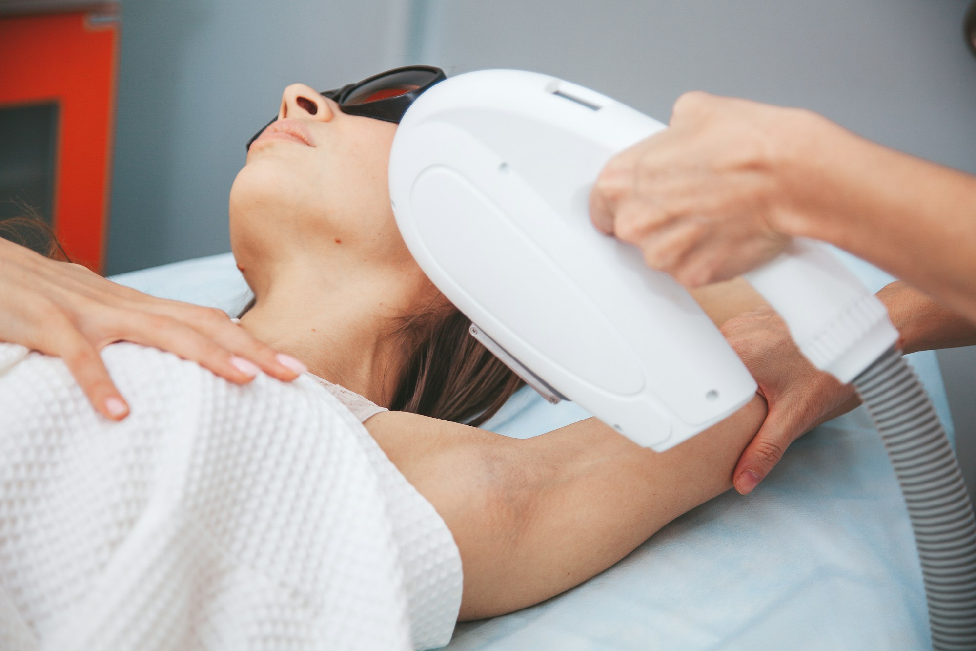 Young woman at beauty salon doing laser hair removal on armpits